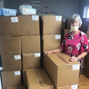 woman smiling next to stacked boxes of supplies